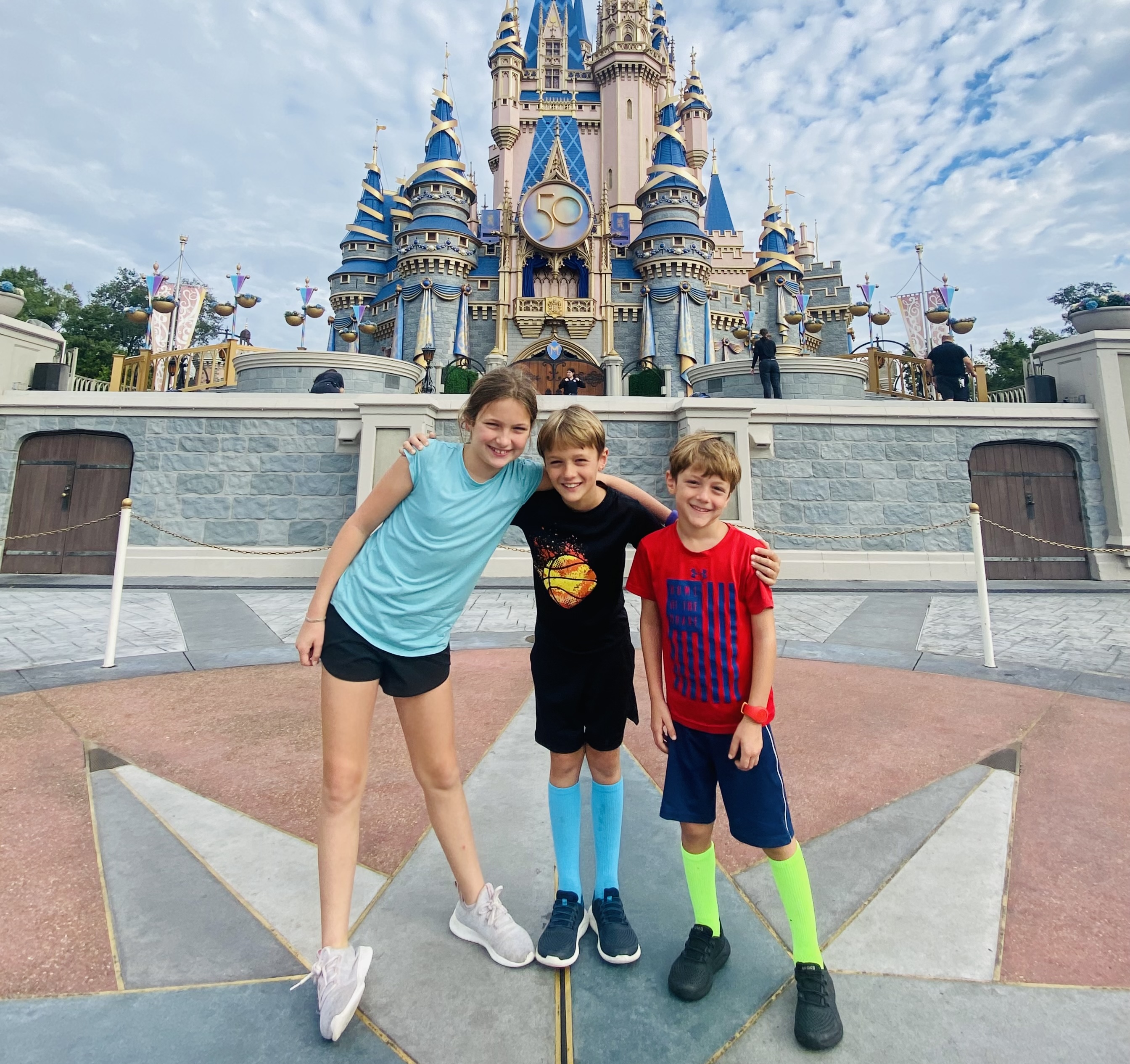 3 kids in front of Cinderella's castle